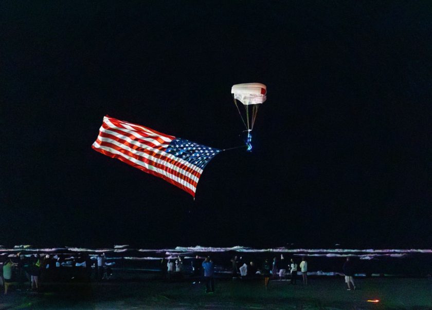 Team Fastrax parachutist carries an American flag over the Ocean City beach at night