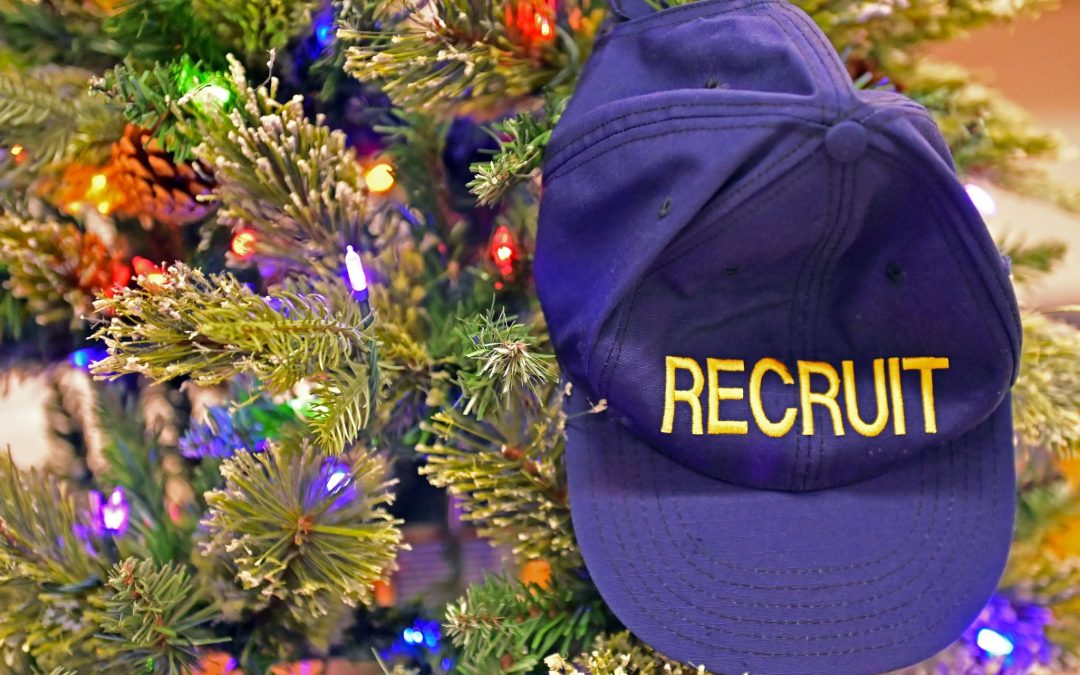 A navy recruit cap rests beside a decorated Christmas tree.